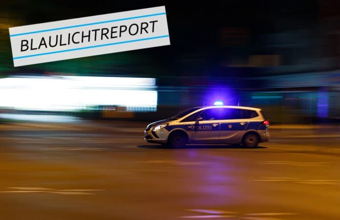 Symbolbild. Ein Polizeiwagen rast mit Blaulicht durch die dunklen Straßen einer Stadt. für den Bericht