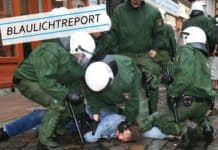 Grausames Familiendrama: Baby aus dem zweiten Stock geworfen Symbolbild. Mehrere Spezialkräfte der Polizei drücken einen überwältigten Mann in blauer Kleidung auf Kopfsteinpflaster.