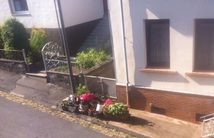 Blick auf Haus mit kleinem Metalltor und Blumen davor und Fußweg.