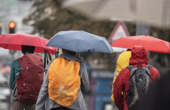 Menschen schützen sich bei Regen mit ihren Schirmen. Foto: Peter Kneffel/dpa/Symbolbild