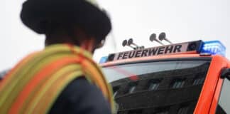 Nach Brand von Wohnhaus: Feuerwehr findet totes Ehepaar Ein Feuerwehrmann mit Schlauch vor einem Feuerwehr-Auto