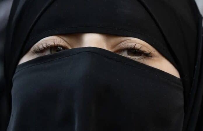 Frau mit schwarzem Niqab, bei dem nur die Augen zu sehen sind. Die Verschleierung verdeckt den Rest ihres Gesichts.