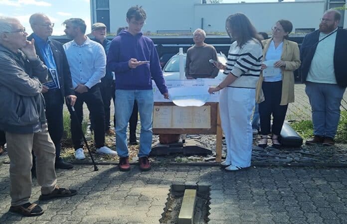 Schüler des HGT präsentieren bei einer Gedenkveranstaltung auf dem Petrisberg die Geschichte des Kriegsgefangenenlagers Stalag XII D vor der ersten Stolperstein-Schwelle in Trier – im Beisein von Vertretern der Stadt und der Benediktinerabtei St. Matthias.