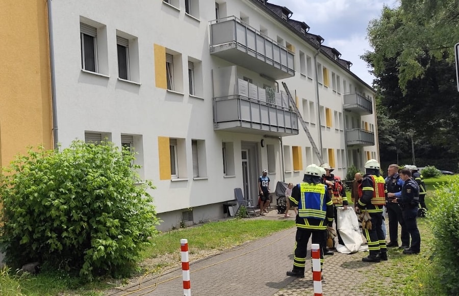 Einsatzkräfte der Feuerwehr und Polizei vor einem Mehrfamilienhaus in Trier nach Rauchentwicklung durch Essen auf dem Herd.
