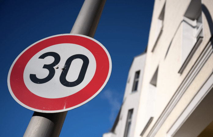 Tempo-30-Schild vor städtischem Wohnhaus bei blauem Himmel – Symbolbild für neue Geschwindigkeitsbegrenzung in Trier.