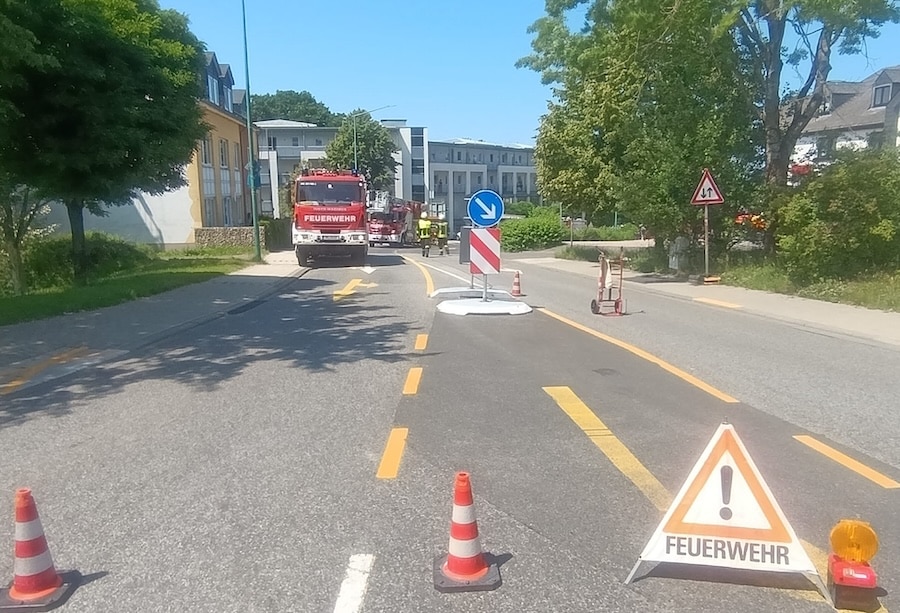 Feuerwehrfahrzeug auf abgesperrter Straße in Hermeskeil, Verkehr mit Pylonen und Warnschild umgeleitet – Blaulicht-Einsatz bei sonnigem Wetter.