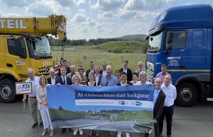 Vertreter der IHK sowie Politik und Kommunen stehen vor einem Banner welches den Lückenschluss der Autobahn 1 in der Eifel fordert.