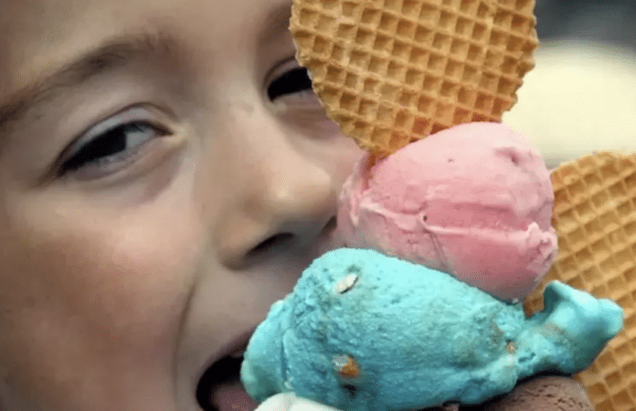 Ein Kind freut sich über zwei Kugeln Speiseeis im Waffelhörnchen