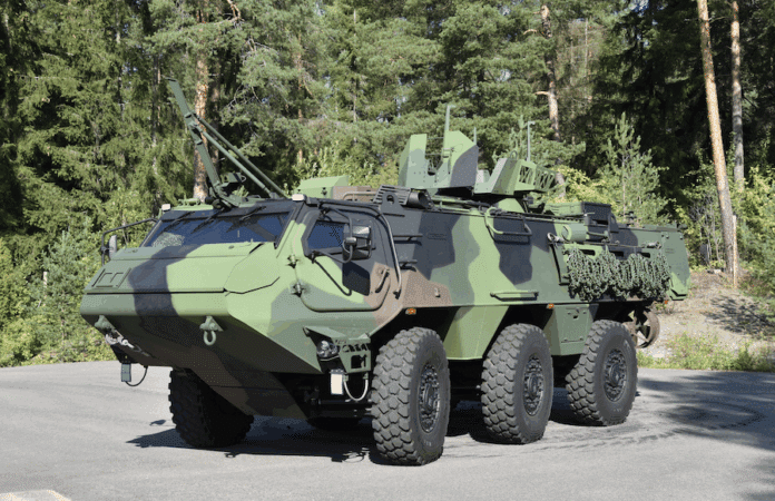 Ein Patria Panzer steht vor einem Waldgebiet.