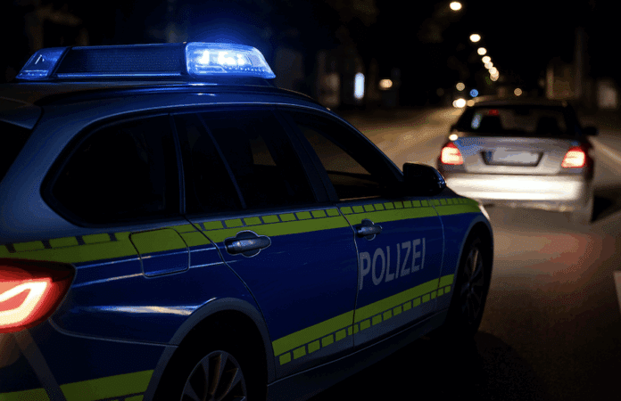 Polizeisperre bei Nacht in Trier nach Verfolgungsfahrt, Einsatzfahrzeug mit Blaulicht auf gesperrter Straße, Symbolbild Polizei-Einsatz.