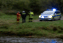 ++ Aktuell: Vermisste Seniorin aus Jünkerath tot in Kyll gefunden ++ Unscharfes Symbolbild eines Flussufers mit Blaulichtreflexionen und einem Einsatzfahrzeug im Hintergrund – erinnert an eine Suchaktion entlang der Kyll in Jünkerath.