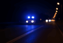 200 km/h Wahnsinn! – Autofahrer entzieht sich der Kontrolle und rast davon! Dunkle Landstraße bei Nacht mit blauem Blaulicht eines Polizeiwagens – Symbolbild für eine Verfolgungsjagd auf der B41 bei Bad Kreuznach.