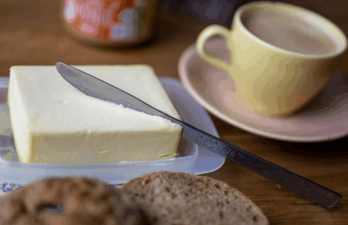 Ein Stück Butter liegt auf einem Teller am Frühstückstisch.