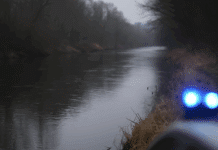 ++ Drama in der Eifel: 72-Jährige tot in der Prüm entdeckt ++ Symbolbild: Flussufer der Prüm an einem trüben Herbsttag, Polizeiabsperrung und Blaulichtreflexionen deuten auf einen Einsatz hin.
