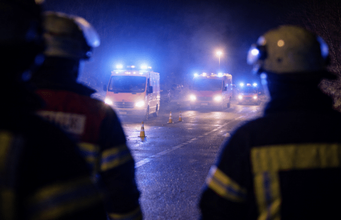 Blaulicht von Polizei und Rettungsdiensten bei nächtlichem Einsatz auf einer gesperrten Straße, Unfallstelle aus der Distanz aufgenommen.