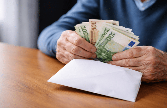 Symbolbild zu Schockanruf-Betrug: Älterer Mann mit Bargeld in einem Briefumschlag