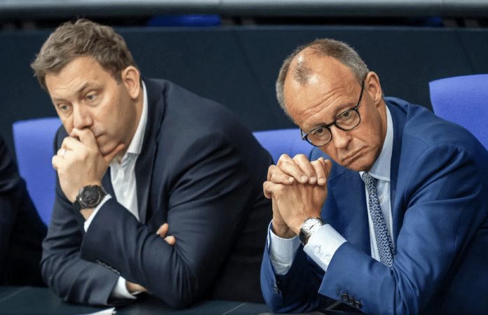 Lars Klingbeil und Friedrich Merz sitzen nebeneinander im Bundestag und verfolgen mit ernstem Blick eine Debatte zum Sondervermögen.